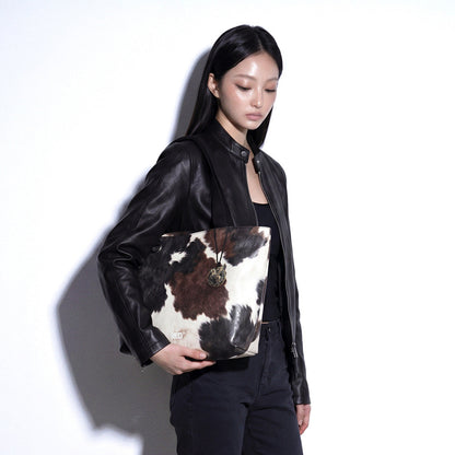 Model holding the EMBER cow print Tyvek tote bag
