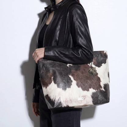 Model wearing the EMBER cow print Tyvek tote bag on shoulder
