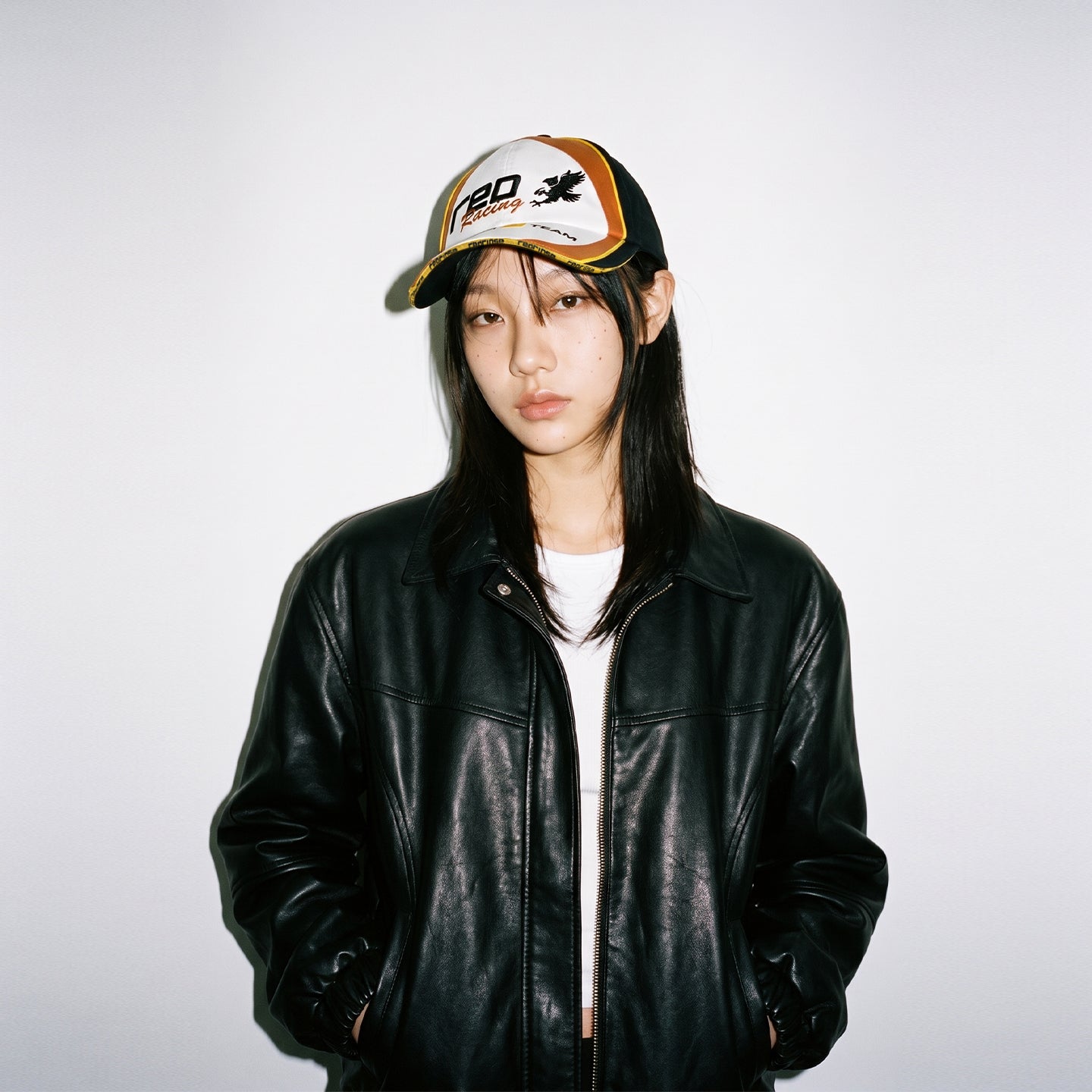Model wearing HORIZON embroidered racing cap with black leather jacket