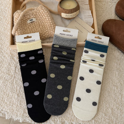 Black charcoal and ivory polka-dot socks in a warm neutral flat-lay